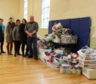 New Beginnings Staff and Androscoggin Staff stand next to the giant pile of donated items for the New Apartment kits.